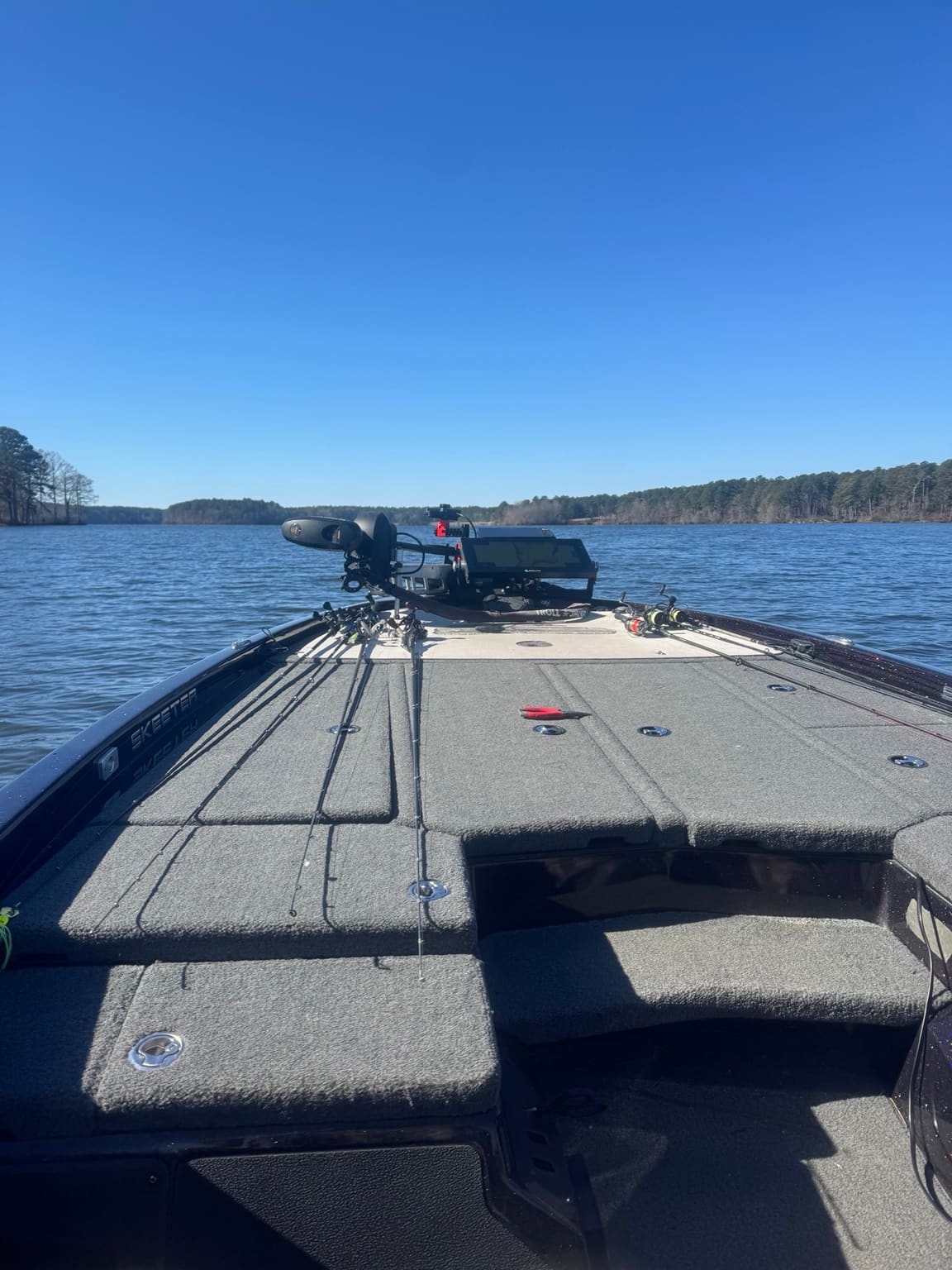 Rods rigged on the front deck of a bass boat on Lake Ouachita under clear skies